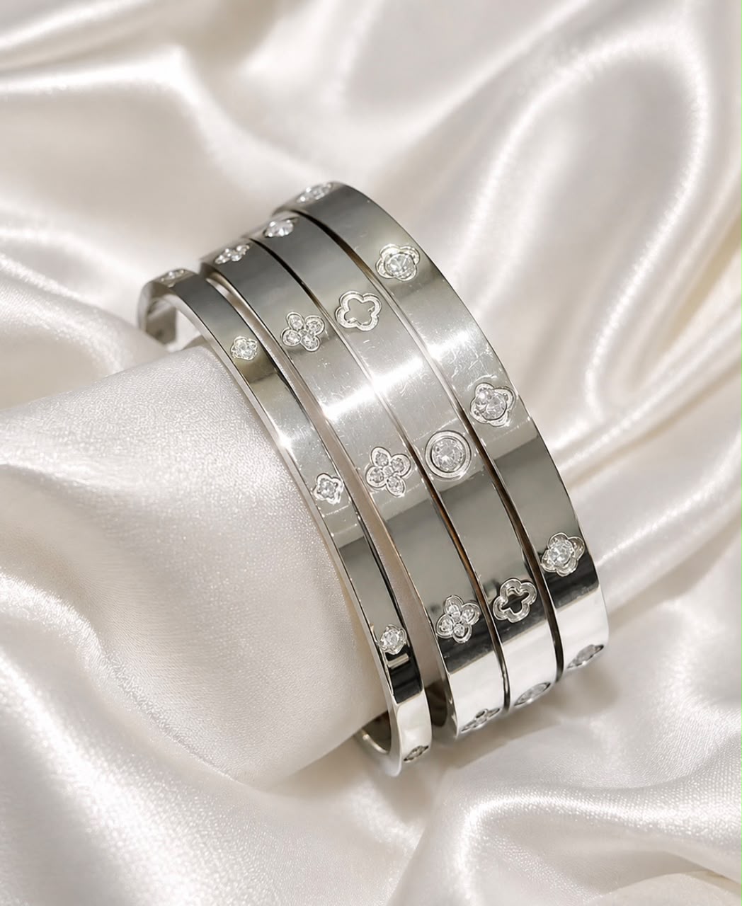 set of four silver plated bangles with clover and crystal detailing