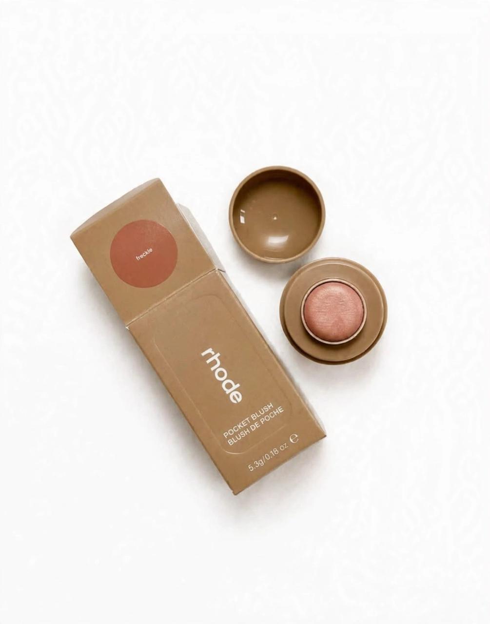 Rhode Pocket Blush in Freckle, open beside its box, on white background